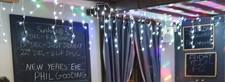 The gig blackboard at the Golden Lion under fairy lights, listing the coming Sunday afternoon sessions